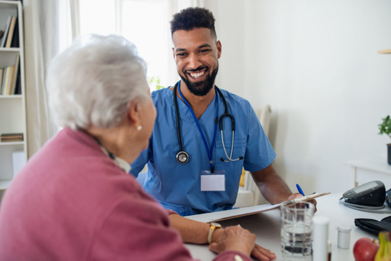 A healthcare professional discusses care needs with an older adult during a medical visit.
