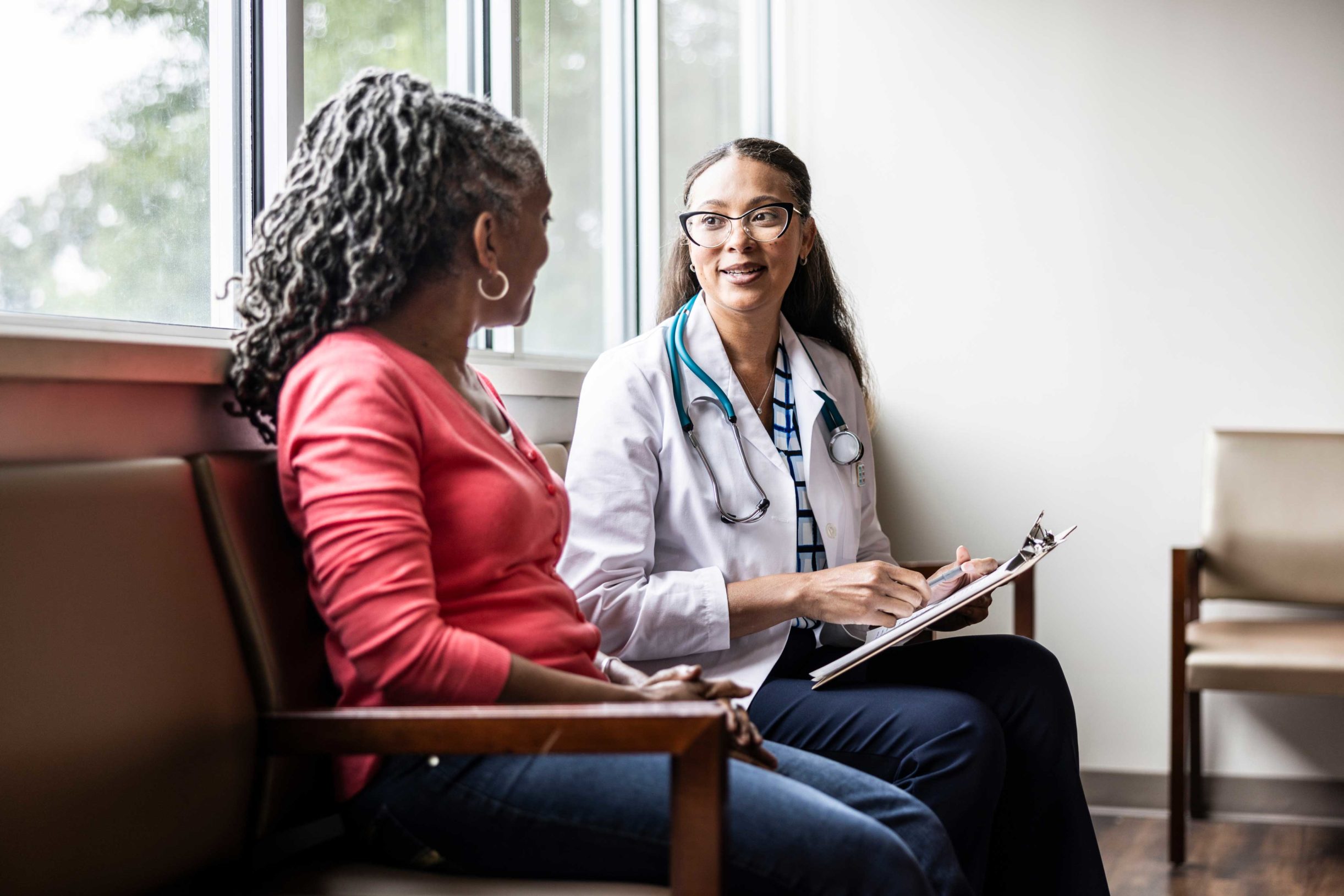 A doctor speaks with a patient about her health and care needs during an office visit.